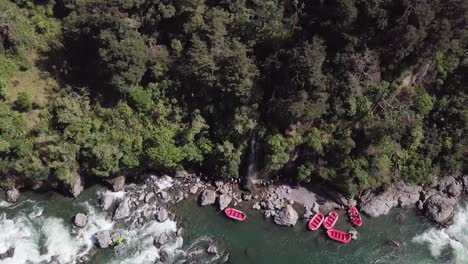 balsas rojas brillantes listas para llevar a los turistas a una experiencia de rafting en aguas bravas en nueva zelanda - vista superior