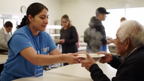volunteers compassionately serve meals to seniors at a community kitchen, demonstrating generosity and kindness through collective efforts and human connection