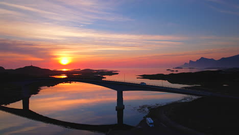 camper van driving over scenic bridge connecting fredvang during midnight sun on lofoten island