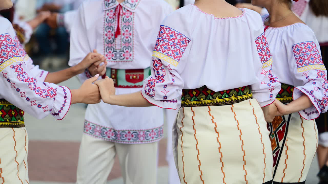Participants dressed in vibrant traditional costumes engage in a folk dance at a cultural festival. Moldavian and Romanian traditional costume