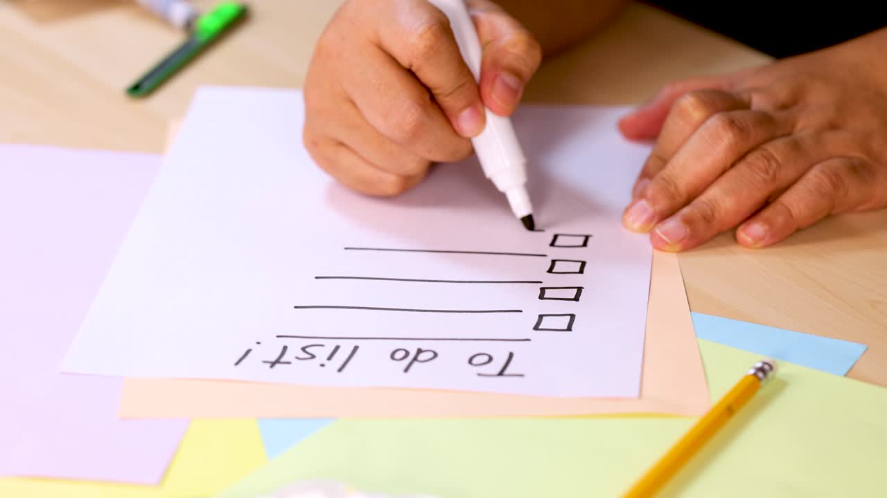 Person draws checklist boxes on to-do list paper with marker, bright lighting, stationary camera
