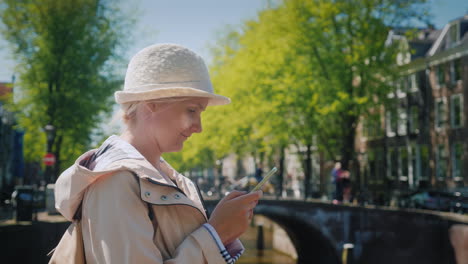 woman uses phone near amsterdam canal