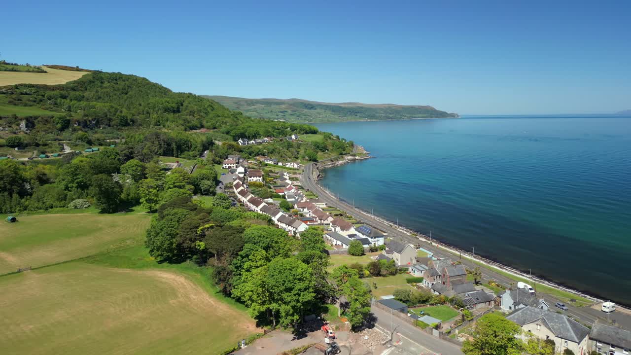 Wide, advancing overhead video of Glenarm and Glenarm Bay, on the Causeway Coastal Route in Northern Ireland, on a bright and sunny day. Filmed in 4K, 60FPS and with Rec709 color.