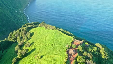 Drone-flies-backward-over-Stunning-lush-ridge-from-Ponta-da-Madrugada-Viewpoint-by-Atlantic-Ocean,-Azores