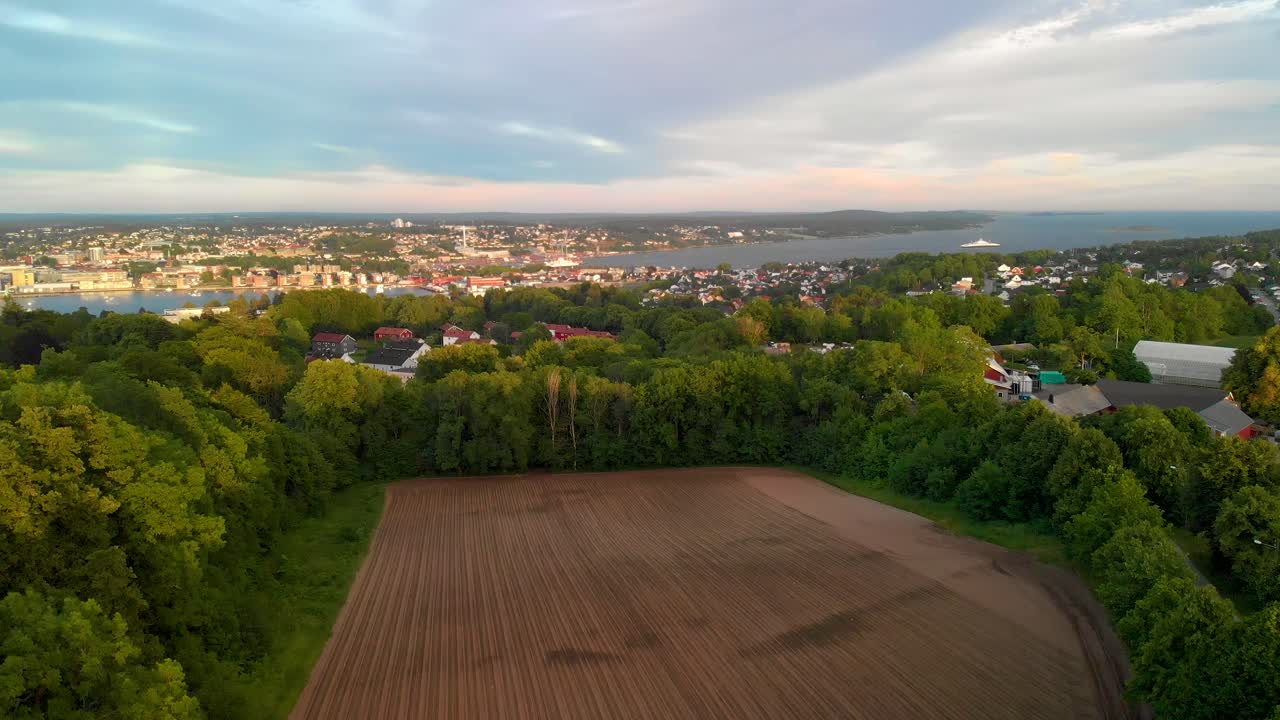 Rising drone shot over Norwegian town with houses, boats and sea in the background