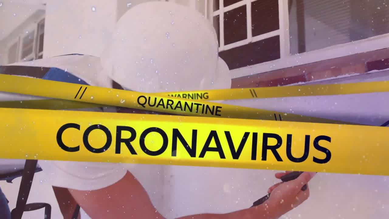 Scritte "Warning Quarantine Coronavirus" su nastro giallo, su un uomo con mascherina sullo sfondo.