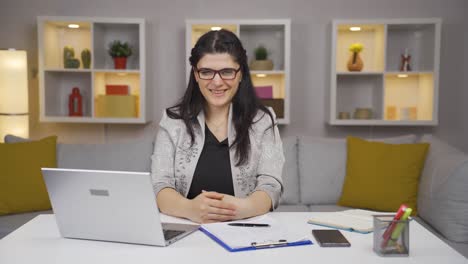 una trabajadora de oficina en casa sonriendo a la cámara.
