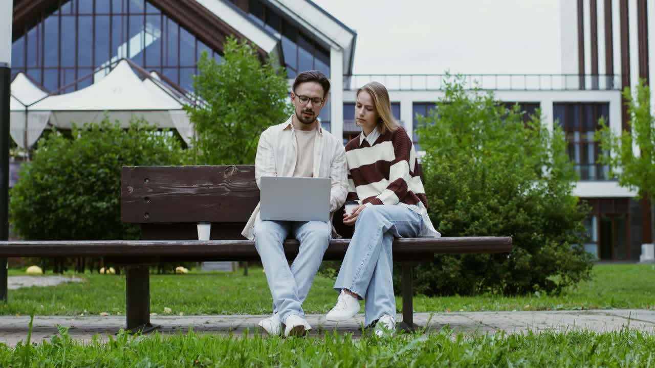 Couple working on laptop outdoors