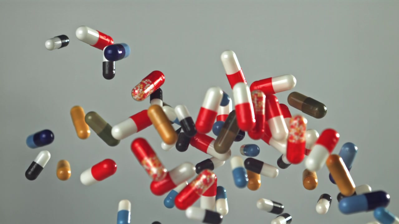 Various Colorful Medical Pills and Capsules Falling in Slow Motion