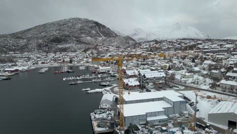 Drohne-Umkreist-Den-Gelben-Kran-Am-Hafen-Des-Fischerdorfes,-Bedeckt-Mit-Schnee,-Arktis