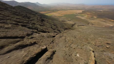 Fuerteventura-Fpv-Buceo-Seco-En-Las-Montañas-Rocosas-Durante-La-Puesta-De-Sol-Cielo-Azul-Cámara-Lenta-50fps