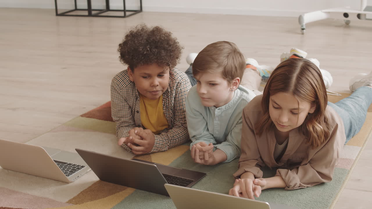 Children Using Computers Lying on Floor