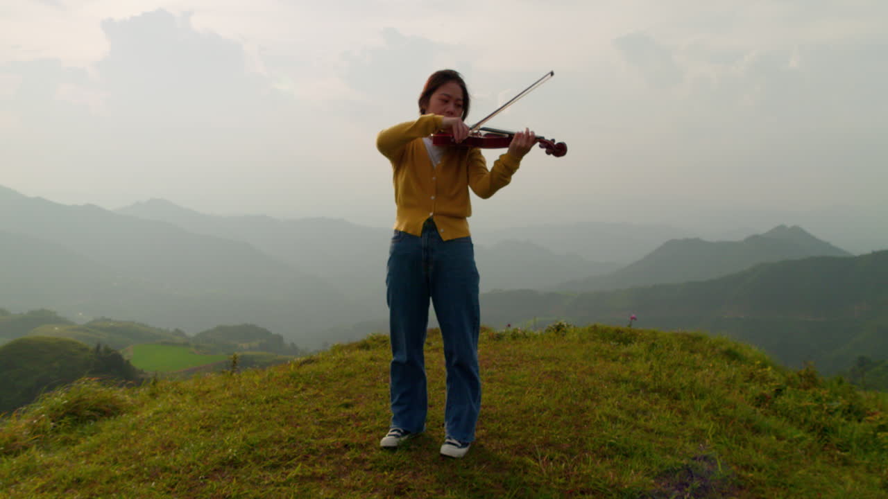 increíble zoom en un primer plano de una mujer tocando el violín en un paraíso en la cima de una montaña