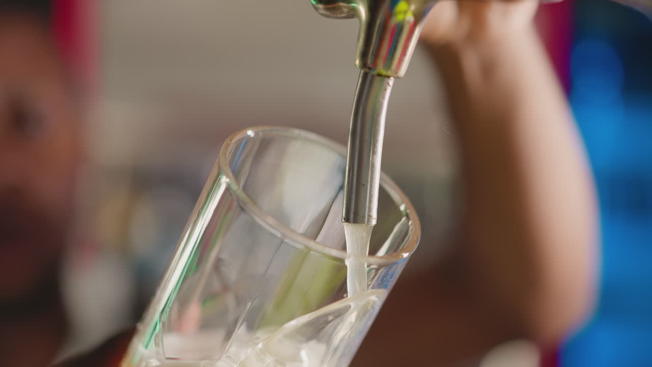 바텐더가 술집에서 맥주 잔을 채우고, 술집 주인이 고객을 위해 술잔에 차가운 음료를 부어주며, 술실에서 축구 팬을 위해 신선한 음료를 제공한다.