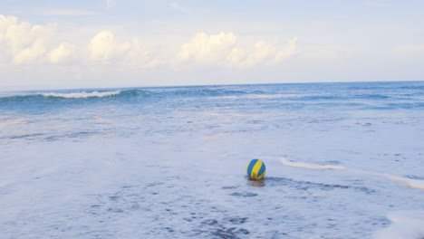 boy picking ball up from the sea.