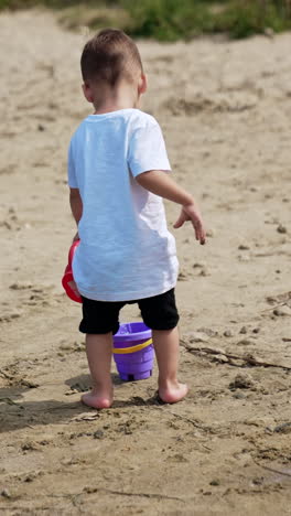 little child summer lifestyle. small boy on river beach playing. vertical video