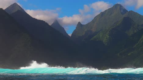 Surfing-surf-barrel-waves-Teahupoo-Tahiti-French-Polynesia-crashing-swell-on-shallow-coral-reef-South-Pacific-island-towering-mountain-peaks-ocean-waterhousing-landscape-blue-sky-super-slow-motion