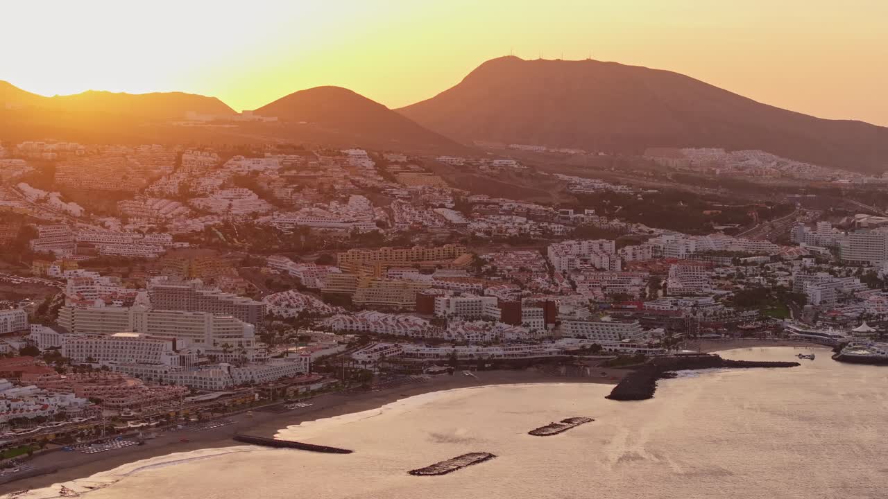 Ripresa con drone di Costa Adeje, Los Cristianos all'alba, luce dorata sulla costa.