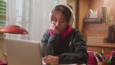 Niña-Escuchando-Música-Con-Auriculares-Mientras-Escribe-En-Su-Cuaderno