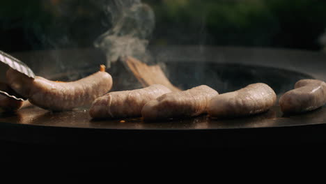 hombre girando salchichas en la parrilla