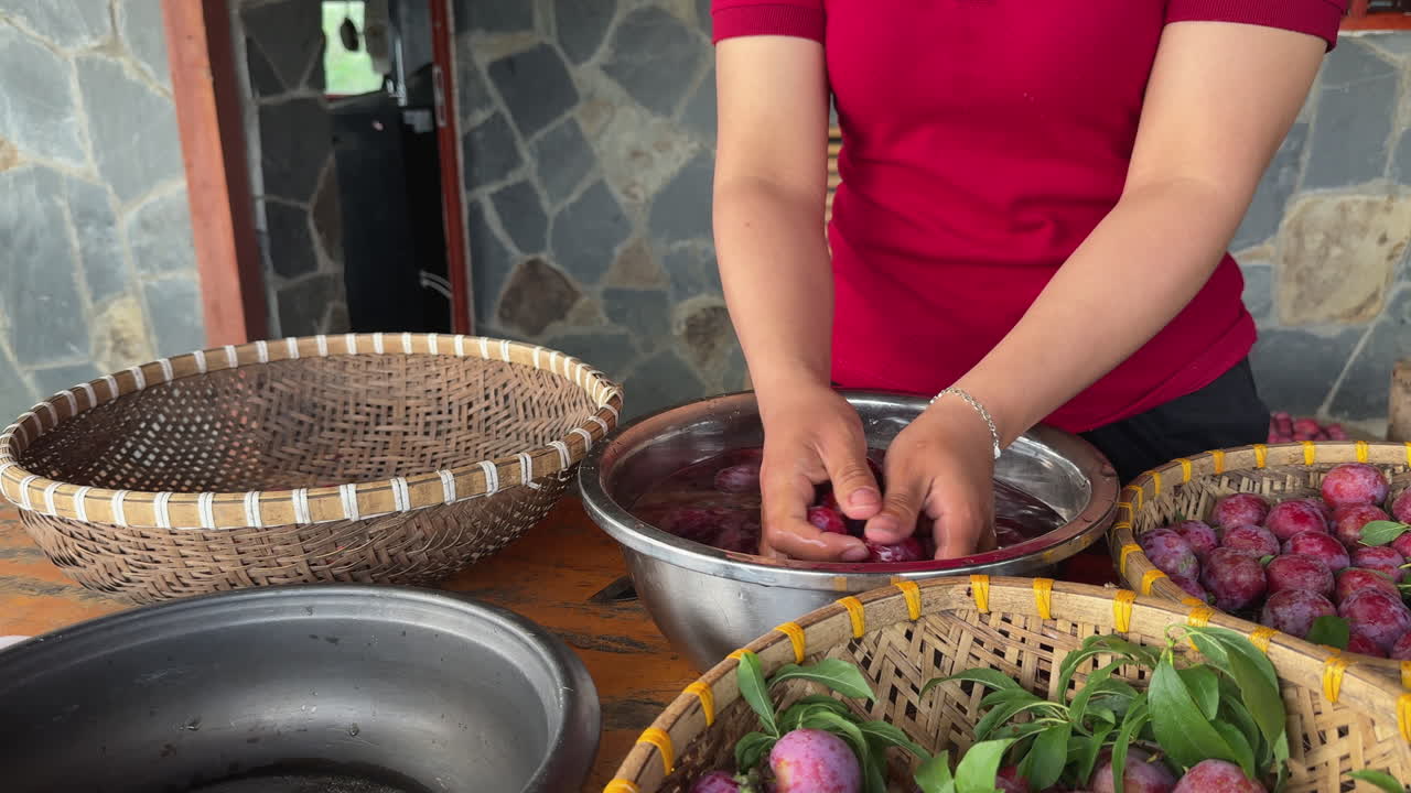 Washing process of fresh red plums by hand in a kitchen using large metal bowl