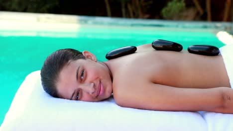 Peaceful-brunette-getting-hot-stone-massage-poolside