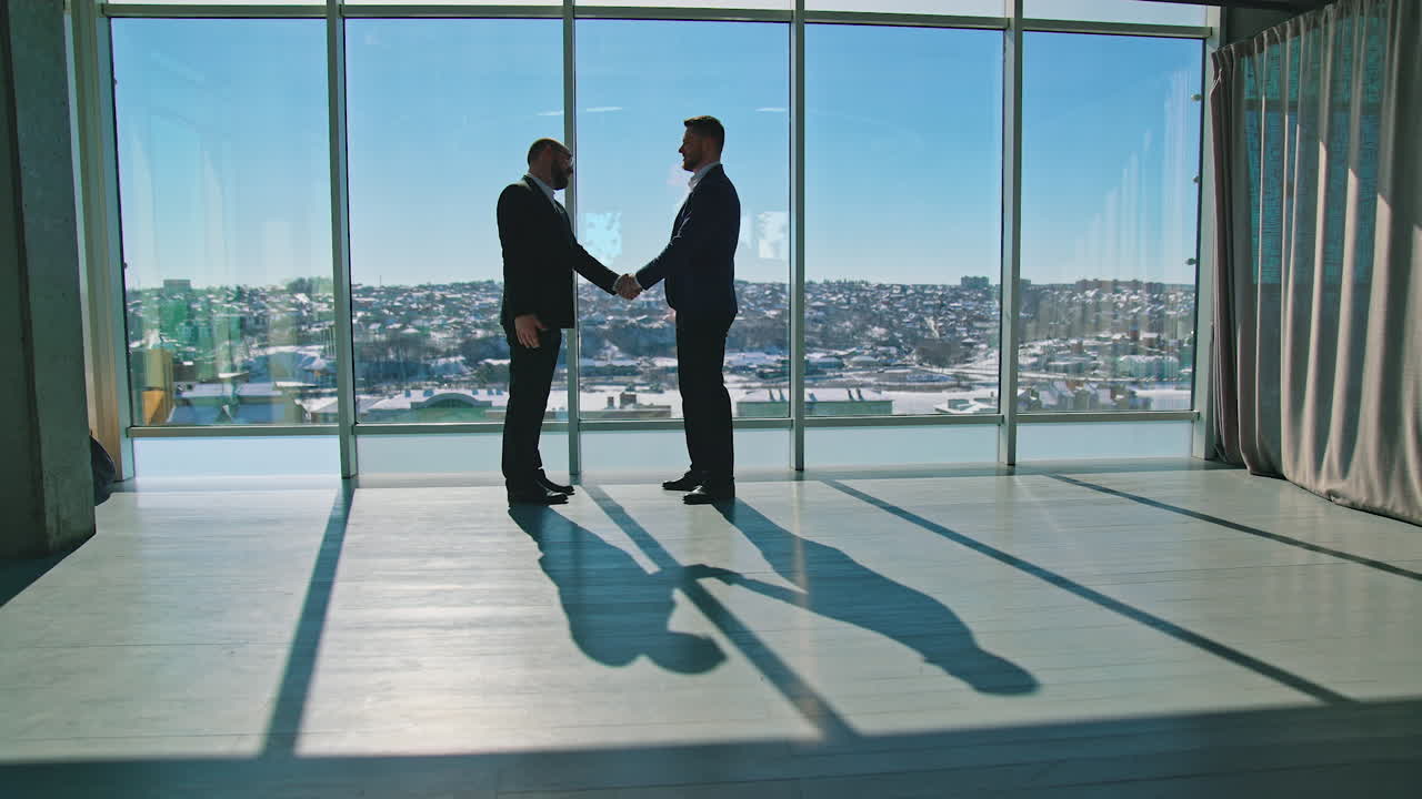 Stretta di mano. Ritratto a figura intera di persone d'affari. Imprenditori in giacca e cravatta eleganti che si incontrano in un ufficio moderno e parlano di affari. Vista laterale. Vista panoramica della città dalle finestre
