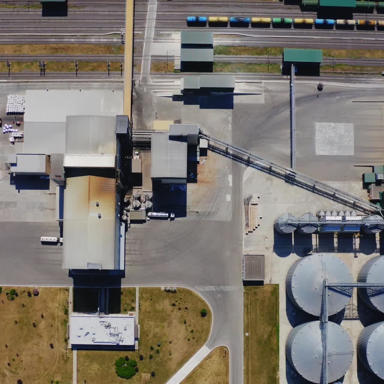 Agricultural plant outdoors. Flight over industrial territory with grain elevators. Granary near the freight station. Top aerial view.