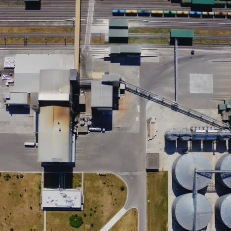 agricultural plant outdoors. flight over industrial territory with grain elevators. granary near the freight station. top aerial view.