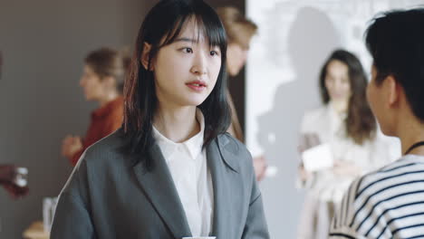 asian woman speaking with female colleague on business event