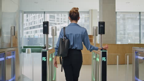 mujer de negocios caminando por la salida de la oficina pasando por el torniquete con el reloj inteligente de vista trasera
