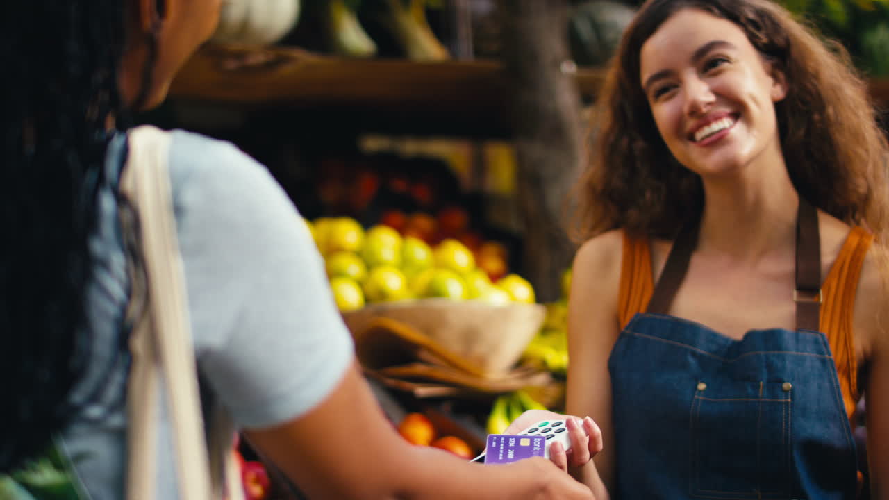 cliente femenina en un puesto de mercado pagando por productos con pago por tarjeta sin contacto