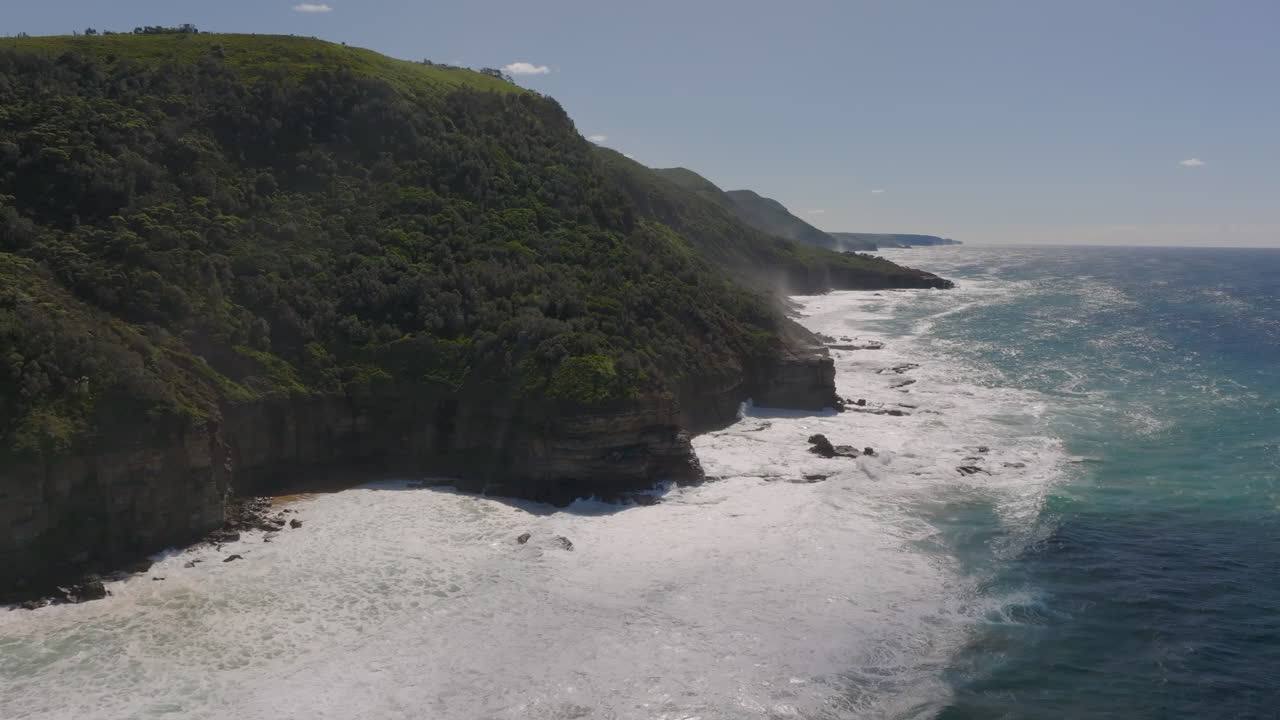Large waves at a rough coastal landscape with dense vegetation at Stanwell Park