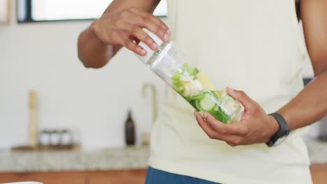 fit african american man cooking, preparing healthy green smoothie