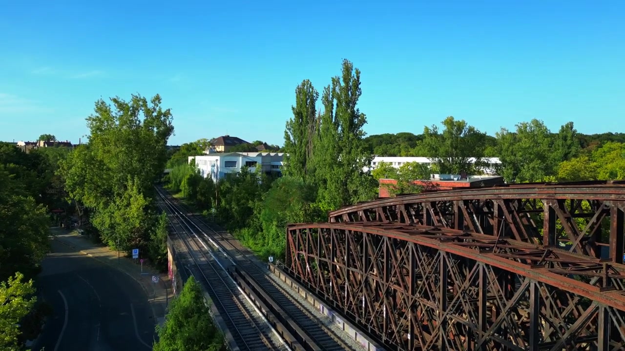 Pont ferroviaire rouillé passant au-dessus de voies ferrées dans un cadre urbain verdoyant à Berlin, Allemagne, infrastructure de transport. Magnifique vue aérienne, survol par drone