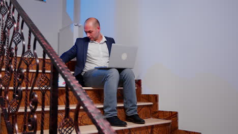 businessman on stairs writing on laptop overtime