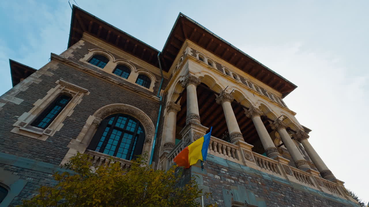 Old-fashioned brick building with columns and arched windows. Building interior with Romanian flag. Low angle view.