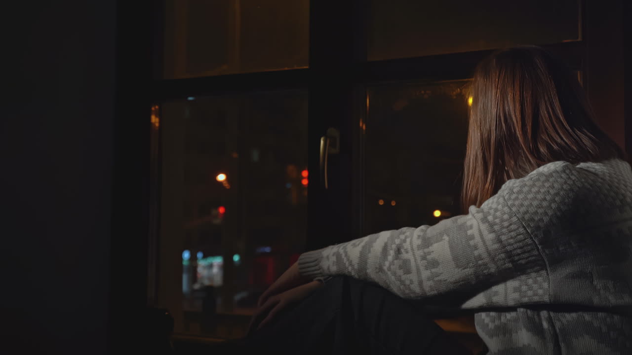 밤에 창문 에 앉아 있는 여자