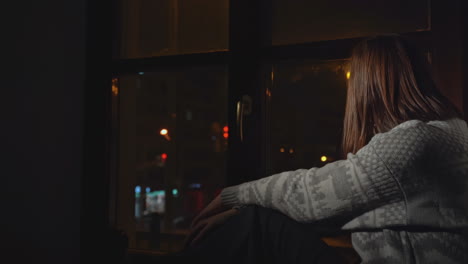 woman sitting by window at night