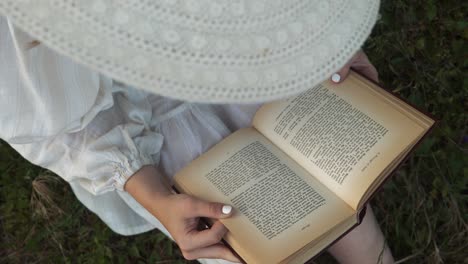 book lover in white sunhat and dress reading novel in rural tranquility