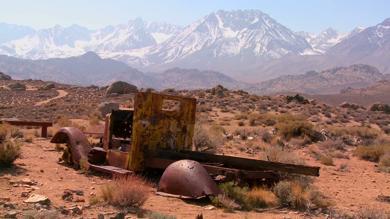 camioneta abandonada con las montañas nevadas de sierra nevada con el sol brillando a través de las nubes