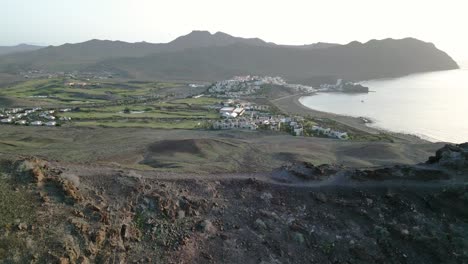 Drone-flying-over-mountain-reveals-the-amazing-Playitas-Resort-on-the-Fuerteventura-Island,-Spain