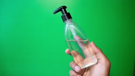 close up of man holding sanitizer gel against green background