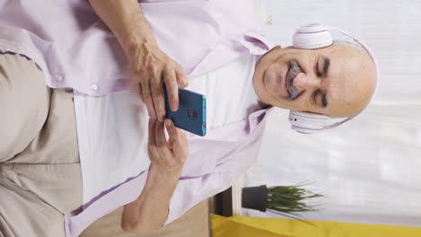 video vertical de un anciano feliz escuchando música con auriculares.