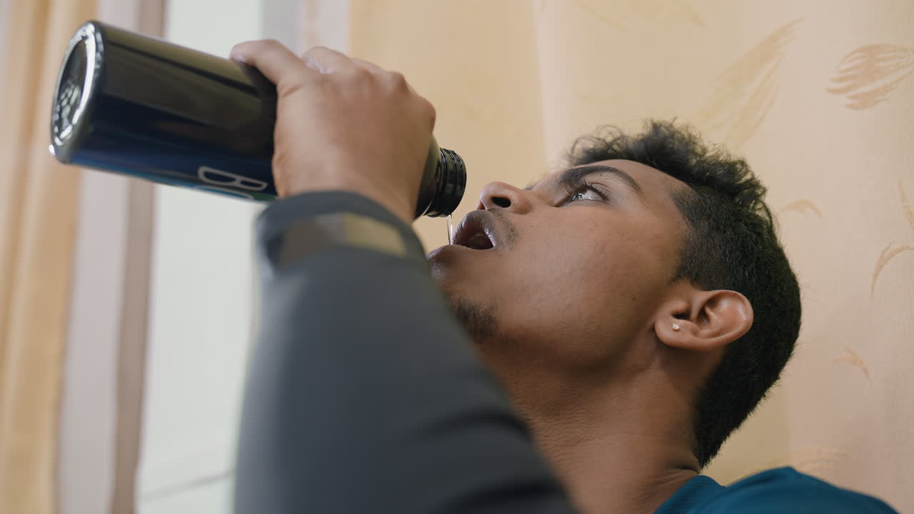Close up of tennis player drinking water from bottle after training, emphasizing hydration, refreshment, and recovery during sports practice, highlighting endurance, discipline