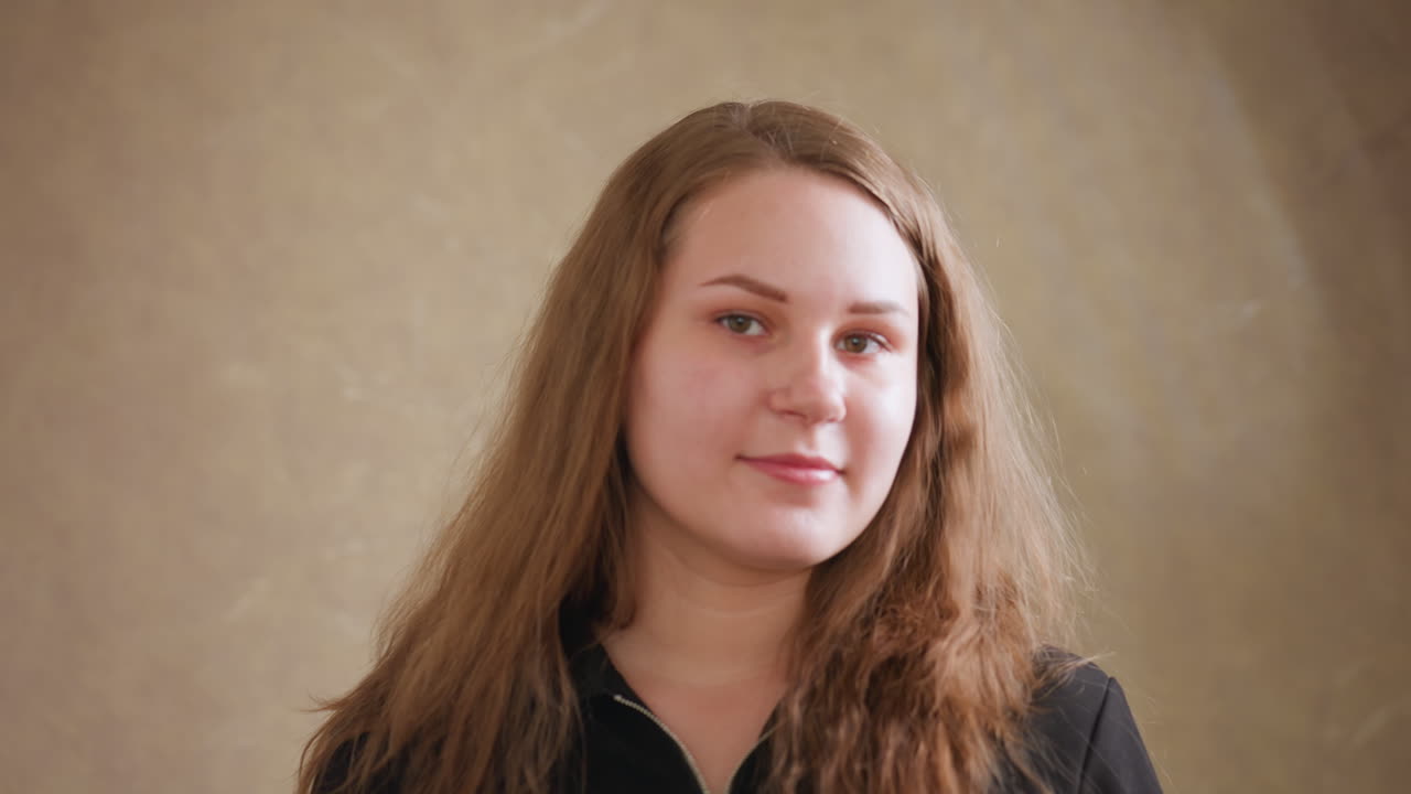 Portrait close up of beautiful young girl in black gown with front zipper, adjusting hair and posing with warm smile in modern doorway, confident look, soft light, natural beauty and elegance
