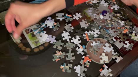 hands assembling jigsaw puzzle,help support in teamwork, close up top down