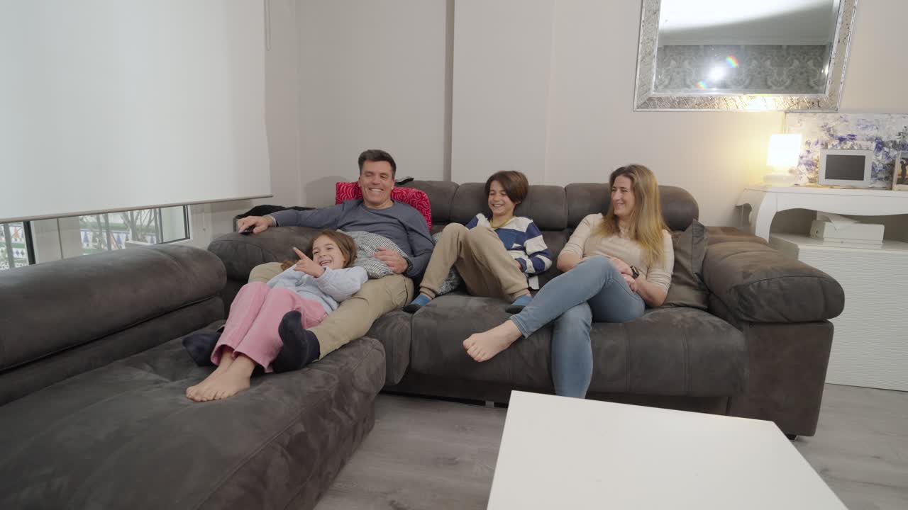 Happy Family Relaxing and Watching TV Together on the Couch