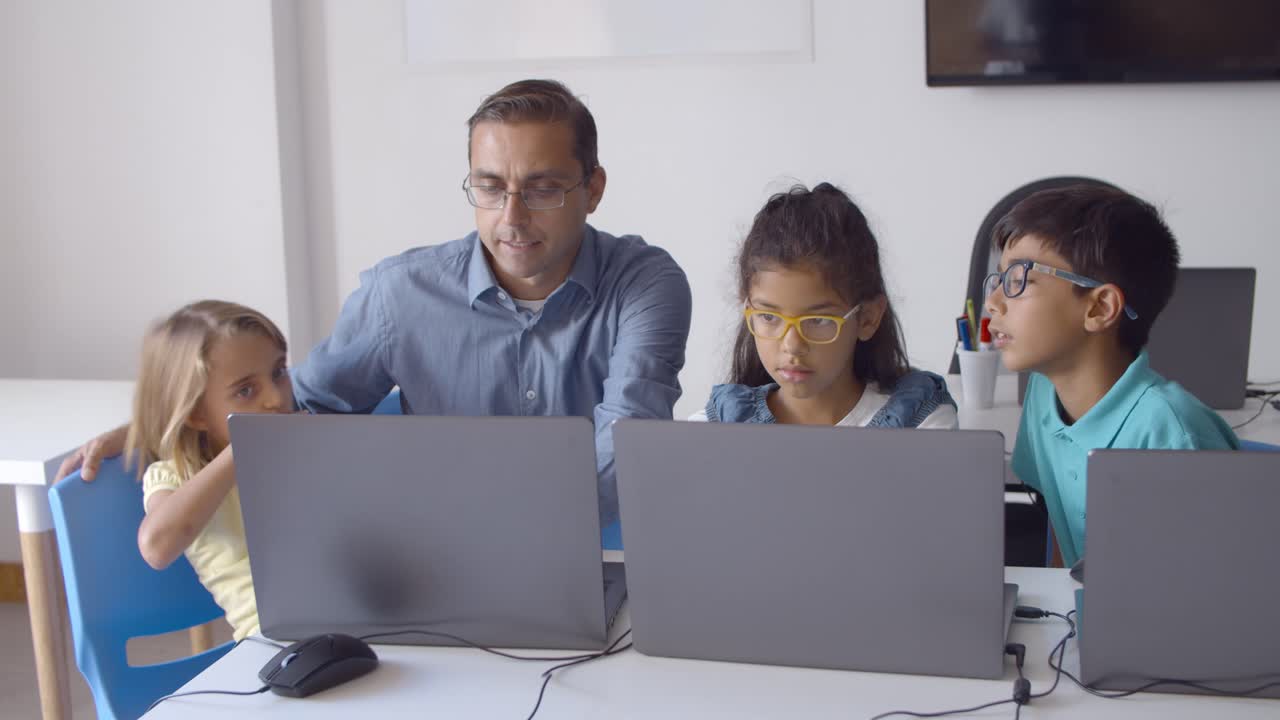 maestro de escuela sentado en el escritorio cerca de un grupo de niños