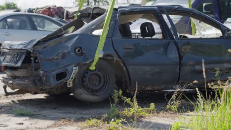 destroyed car frame is lifted with heavy crane in scrapyard, side view